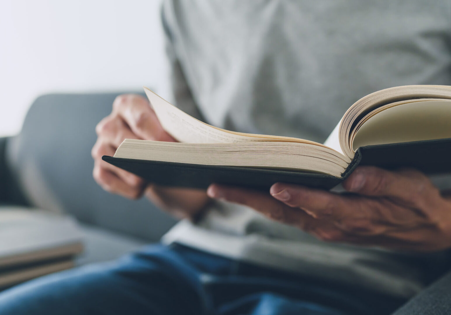 Man working or studying with book . Business and education concept Person sitting on a couch, holding and reading an open book.
