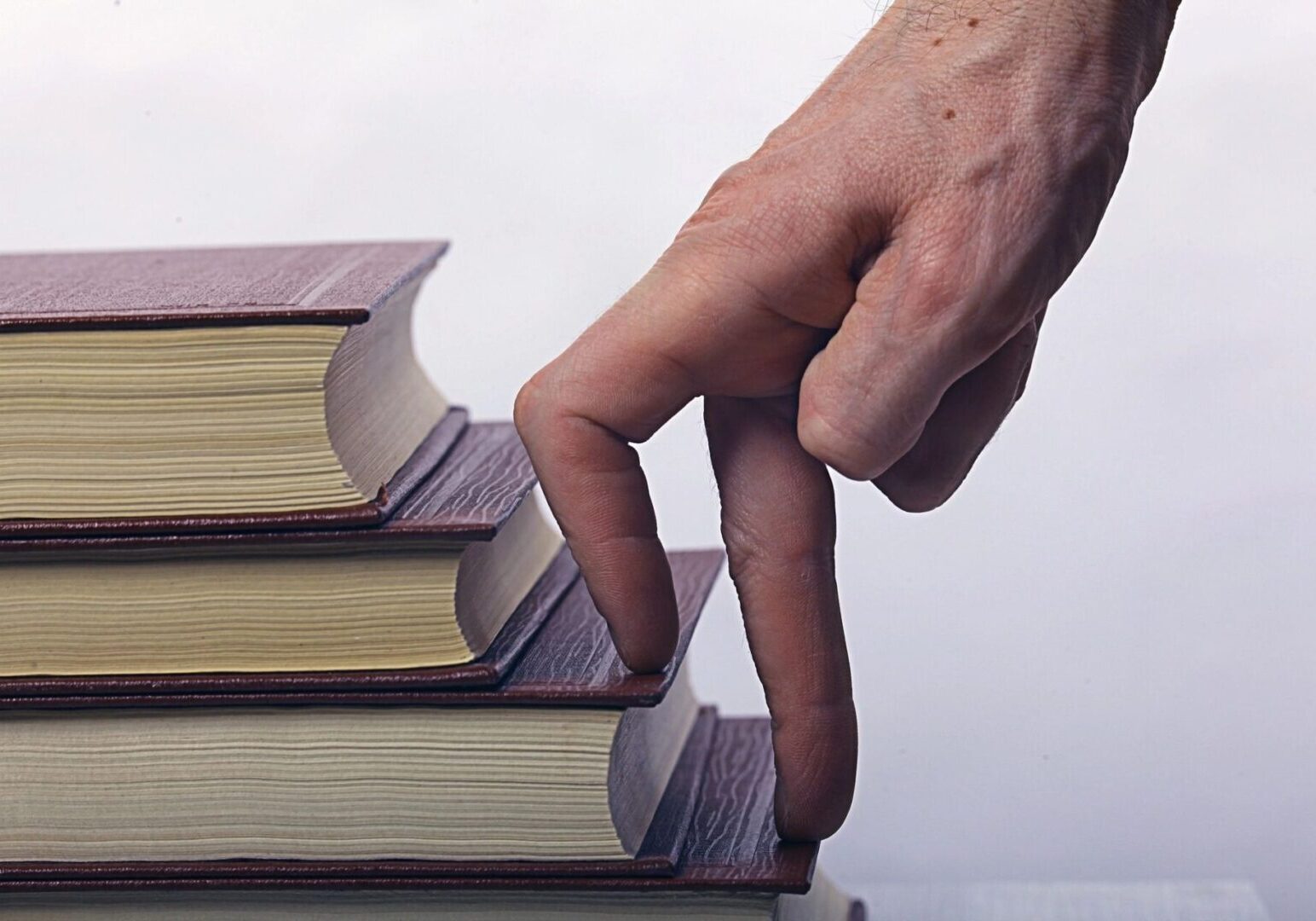 fm=f_6031 Fingers walking up a stack of four books arranged in ascending order.